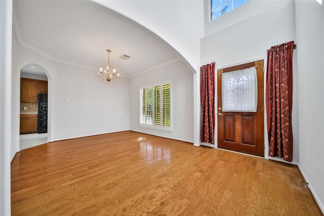 entrance foyer with crown molding, light hardwood / wood-style flooring, and a notable chandelier