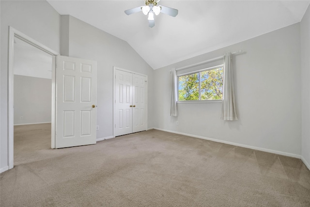 unfurnished bedroom featuring ceiling fan, light colored carpet, lofted ceiling, and a closet