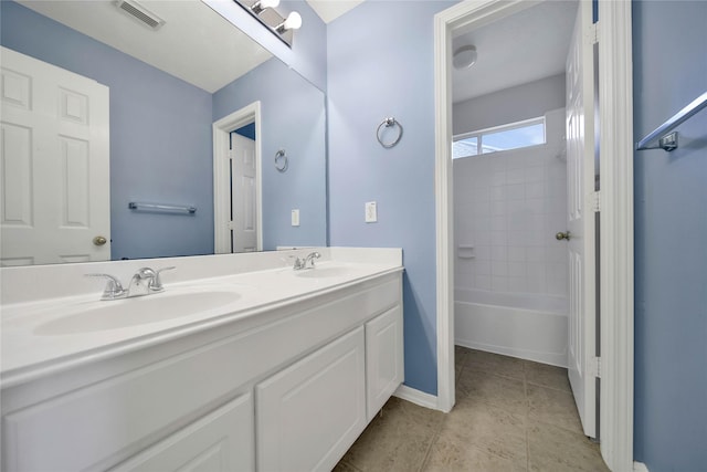 bathroom with tile patterned flooring, vanity, and tiled shower / bath