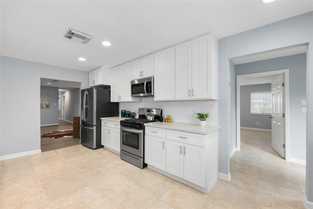 kitchen featuring backsplash, light tile patterned floors, light stone countertops, appliances with stainless steel finishes, and white cabinetry