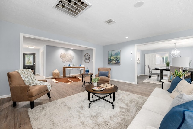 living room featuring an inviting chandelier, a textured ceiling, and light wood-type flooring