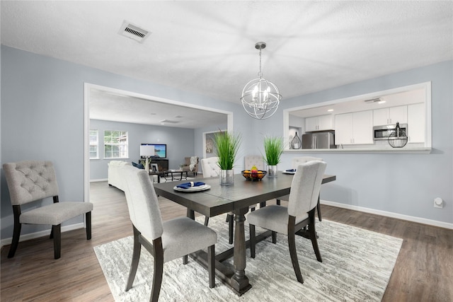 dining room with an inviting chandelier, a textured ceiling, and hardwood / wood-style flooring