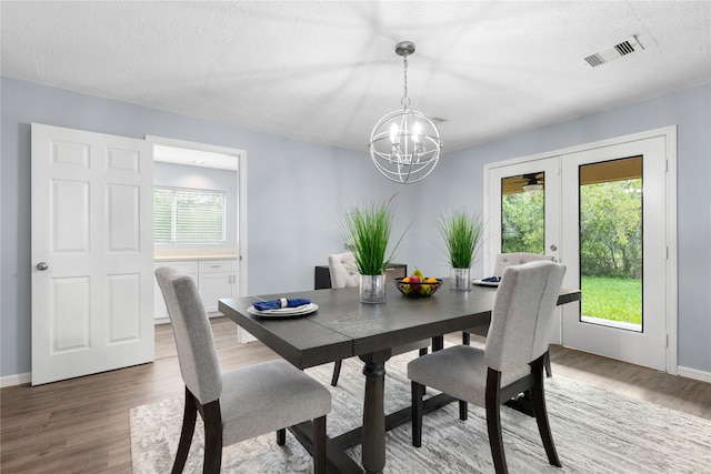 dining space with hardwood / wood-style floors, a notable chandelier, and a textured ceiling