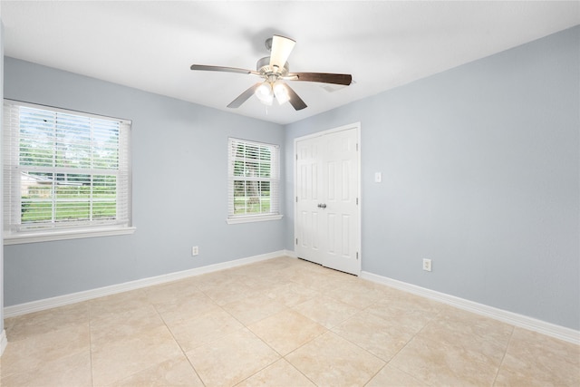 tiled spare room featuring ceiling fan