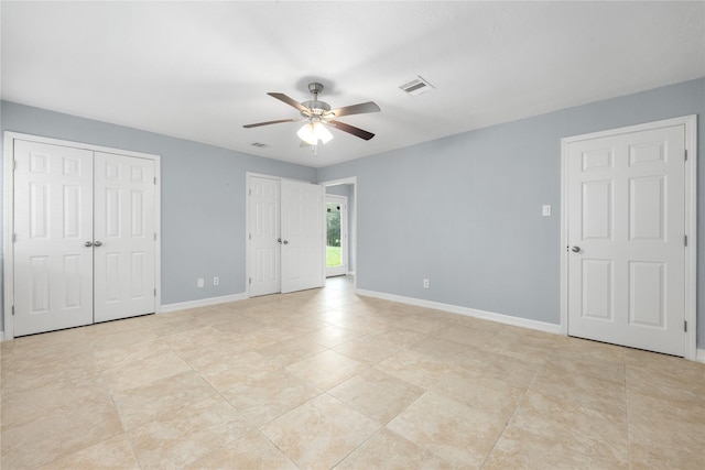 unfurnished bedroom featuring two closets and ceiling fan