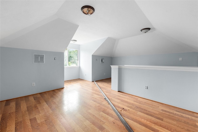 additional living space with light hardwood / wood-style flooring and vaulted ceiling