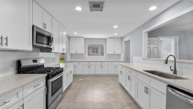 kitchen with light stone countertops, white cabinetry, sink, and appliances with stainless steel finishes