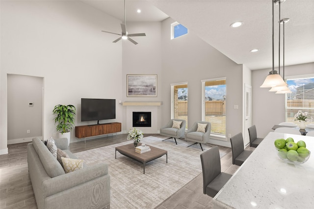 living room with light wood-type flooring, high vaulted ceiling, and ceiling fan