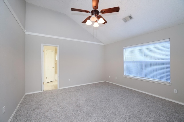 empty room featuring ceiling fan, light colored carpet, vaulted ceiling, and a textured ceiling