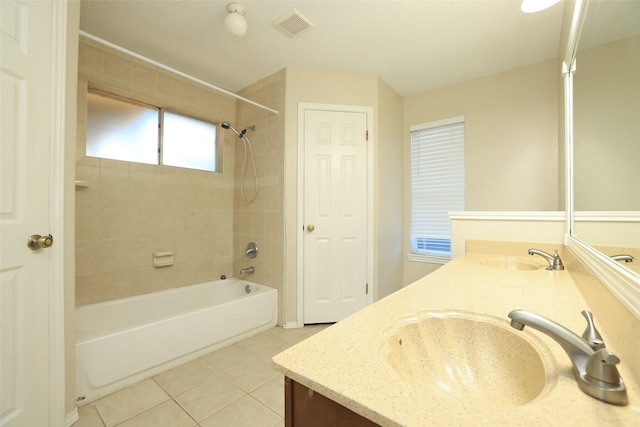 bathroom featuring tiled shower / bath, vanity, and tile patterned flooring