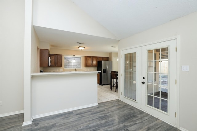 kitchen featuring french doors, lofted ceiling, stainless steel fridge, kitchen peninsula, and light hardwood / wood-style floors