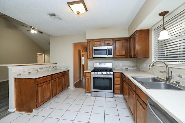 9130 Kirkleigh St, Spring, TX 77379 - kitchen featuring stainless steel appliances, a sink, ceiling fan, light countertops, and brown cabinetry