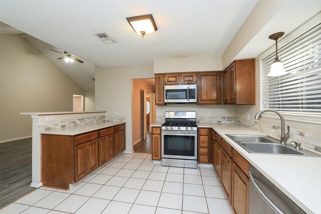 kitchen with sink, decorative light fixtures, light tile patterned floors, kitchen peninsula, and stainless steel appliances