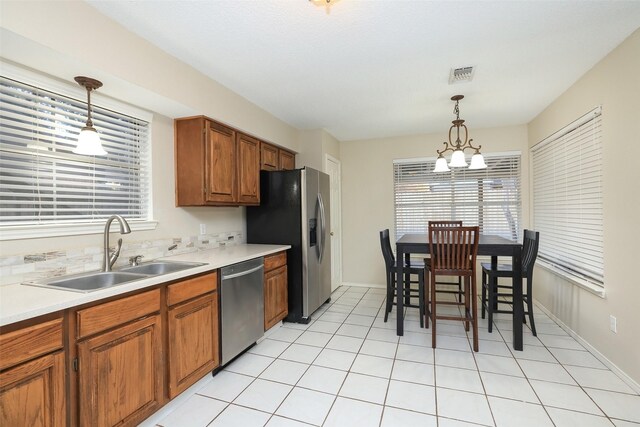 kitchen with pendant lighting, appliances with stainless steel finishes, sink, and a notable chandelier