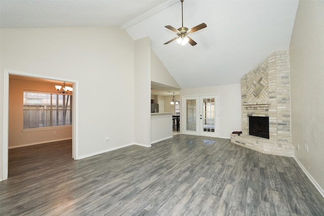 unfurnished living room with french doors, high vaulted ceiling, dark hardwood / wood-style flooring, a fireplace, and ceiling fan with notable chandelier