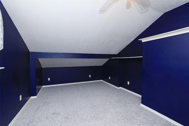 additional living space featuring a textured ceiling, vaulted ceiling, ceiling fan, and carpet flooring