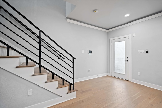 entryway with light hardwood / wood-style flooring and crown molding