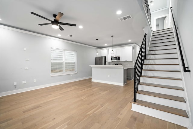 unfurnished living room with light hardwood / wood-style flooring, ceiling fan, and crown molding