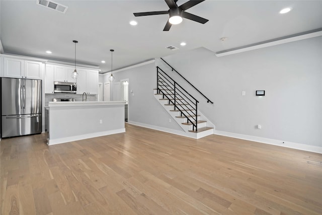 unfurnished living room with ceiling fan, light hardwood / wood-style flooring, and crown molding