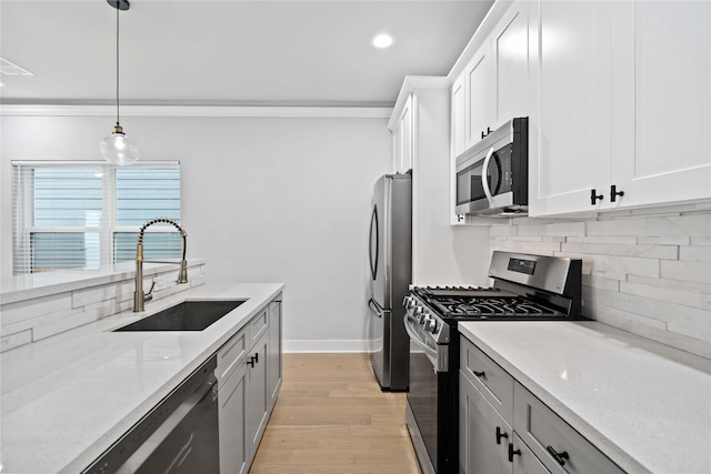 kitchen with pendant lighting, sink, light stone countertops, appliances with stainless steel finishes, and white cabinetry