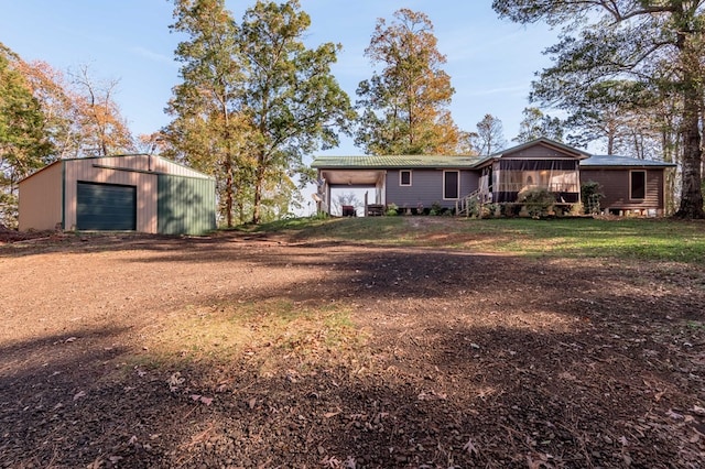 rear view of house with a sunroom, a garage, and an outbuilding