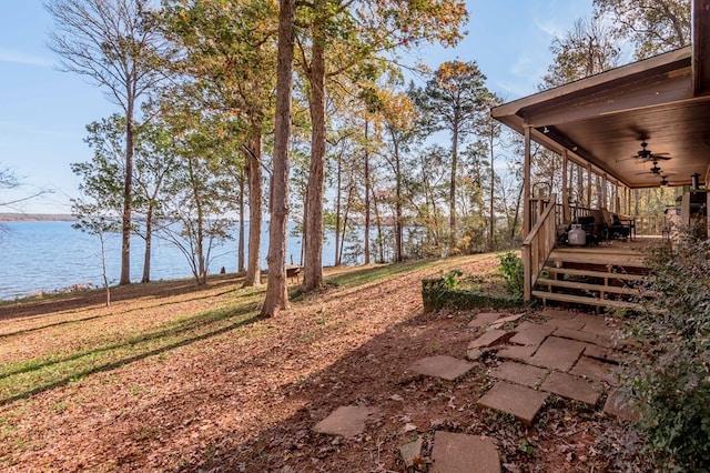 view of yard with ceiling fan and a water view