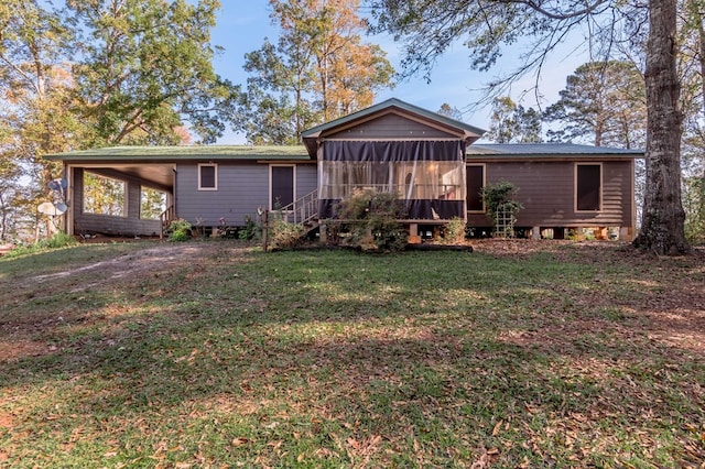 rear view of house with a sunroom, a carport, and a yard