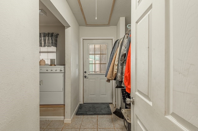 doorway featuring light tile patterned flooring, washer / dryer, and a textured ceiling