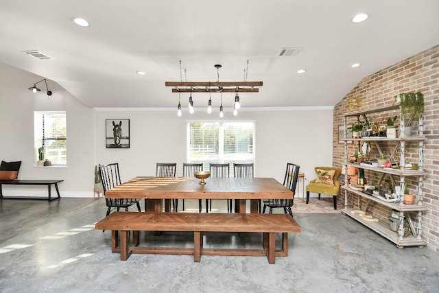 dining room with concrete flooring, brick wall, and vaulted ceiling