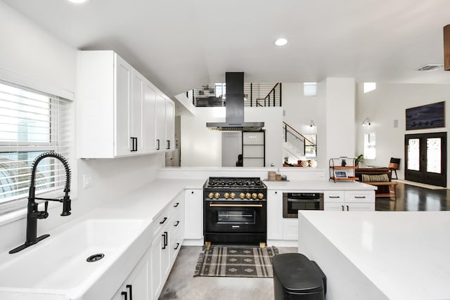 kitchen featuring white cabinetry, sink, high end stove, oven, and extractor fan