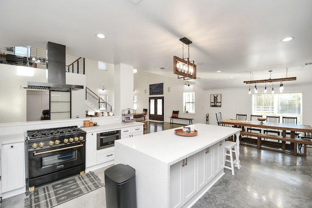 kitchen featuring high end range, concrete floors, decorative light fixtures, island range hood, and white cabinets