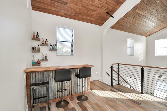 bar with lofted ceiling, light wood-type flooring, and wood ceiling