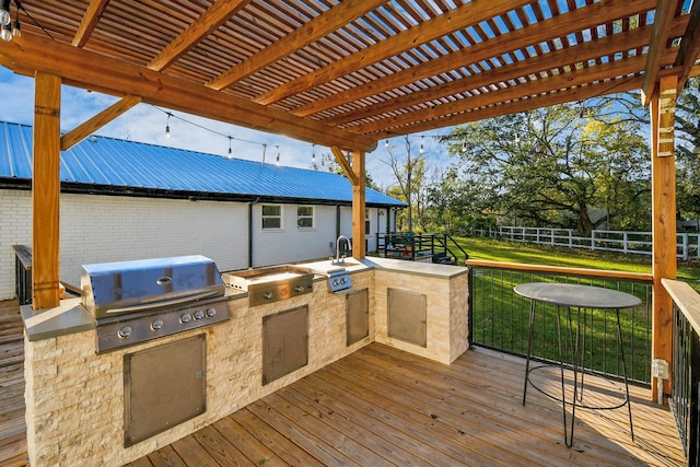 wooden deck featuring an outdoor kitchen, area for grilling, a pergola, and a yard