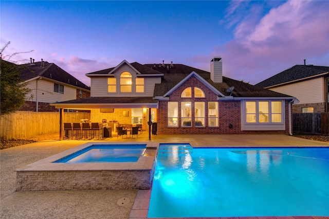 pool at dusk with cooling unit, an outdoor bar, an in ground hot tub, and a patio