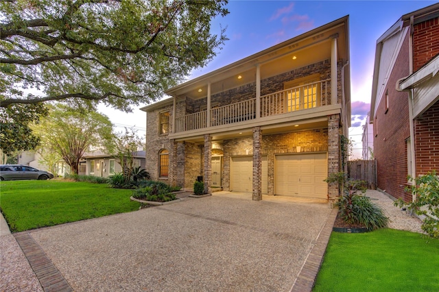 view of front of home featuring a yard, a balcony, and a garage