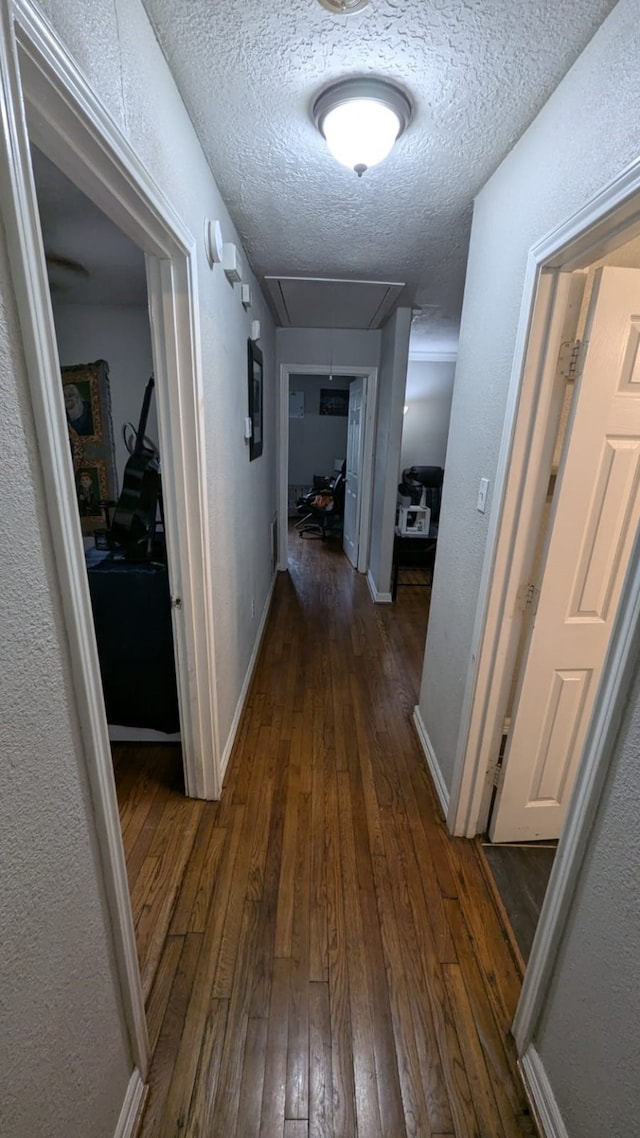 hall featuring a textured ceiling and dark hardwood / wood-style floors