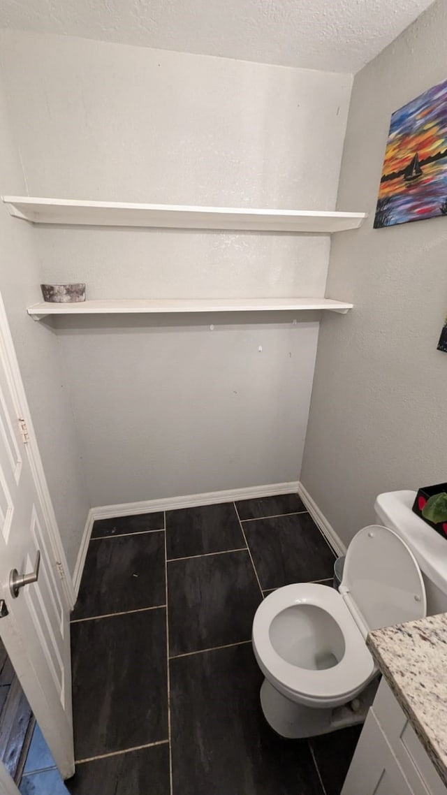 bathroom featuring toilet, a textured ceiling, vanity, and tile patterned floors