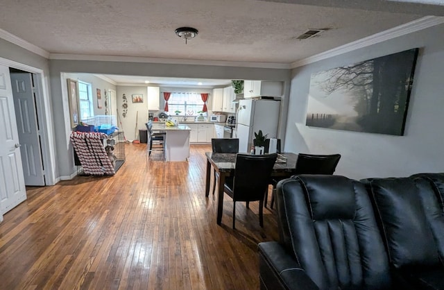 dining room featuring ornamental molding, a textured ceiling, and hardwood / wood-style flooring