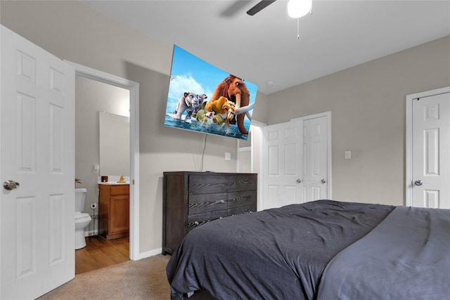 bedroom with ceiling fan, ensuite bathroom, and light carpet