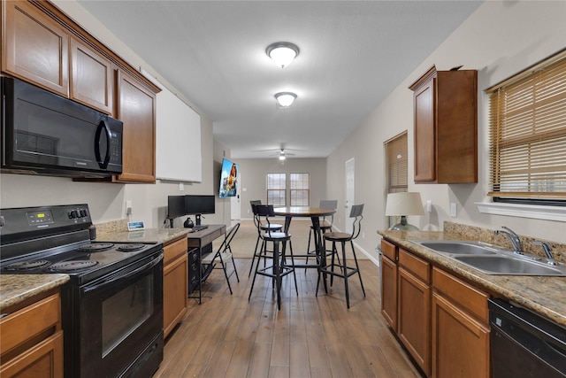 kitchen with ceiling fan, sink, black appliances, and hardwood / wood-style flooring