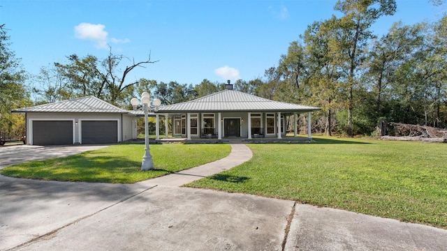 view of front of property featuring covered porch, an outbuilding, a garage, and a front lawn