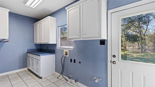 laundry area with hookup for a gas dryer, cabinets, light tile patterned floors, hookup for a washing machine, and electric dryer hookup