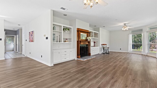 unfurnished living room with ceiling fan, light hardwood / wood-style floors, and a tiled fireplace