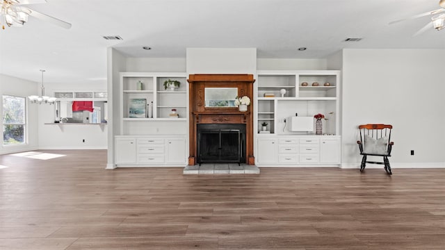 unfurnished living room featuring wood-type flooring and ceiling fan with notable chandelier