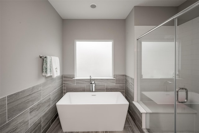 bathroom featuring separate shower and tub and tile walls