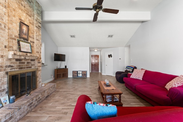 living room featuring ceiling fan, lofted ceiling with beams, wood-type flooring, and a brick fireplace