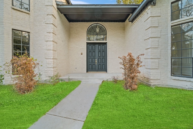 doorway to property featuring a lawn and covered porch