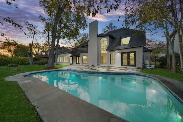 pool at dusk featuring french doors