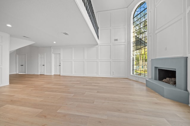 unfurnished living room featuring light hardwood / wood-style floors and a textured ceiling