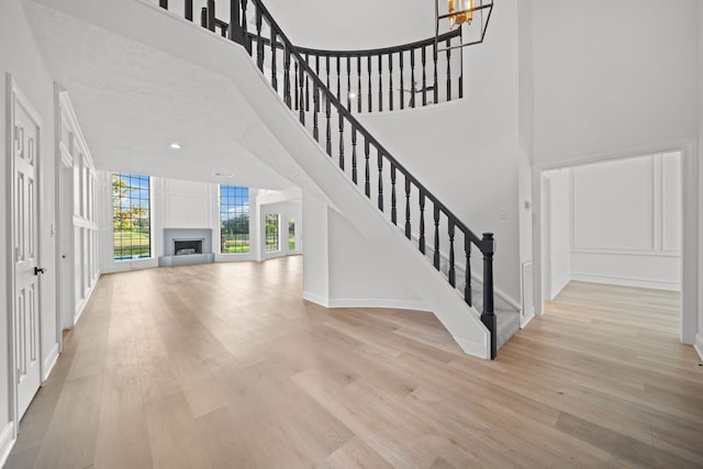 stairway with wood-type flooring, a towering ceiling, a textured ceiling, and a notable chandelier